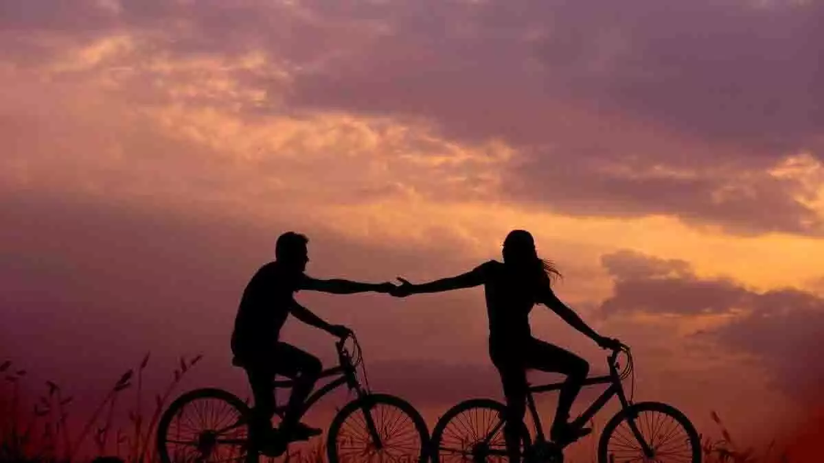 Silueta de una pareja paseando en bici.