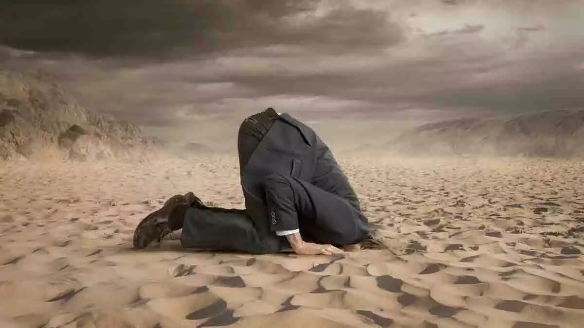 Hombre enterrando la cabeza bajo la arena.