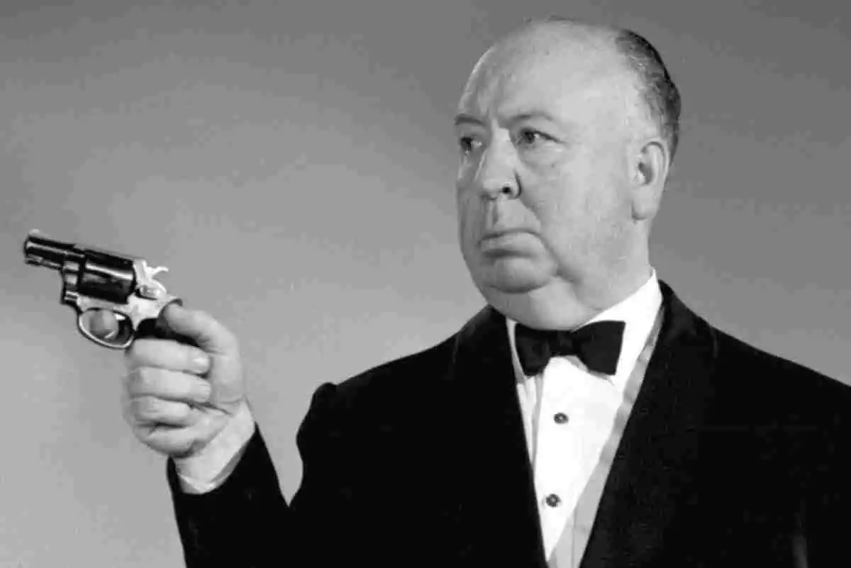 Alfred Hitchcock, maestro del cine, sosteniendo una pistola.