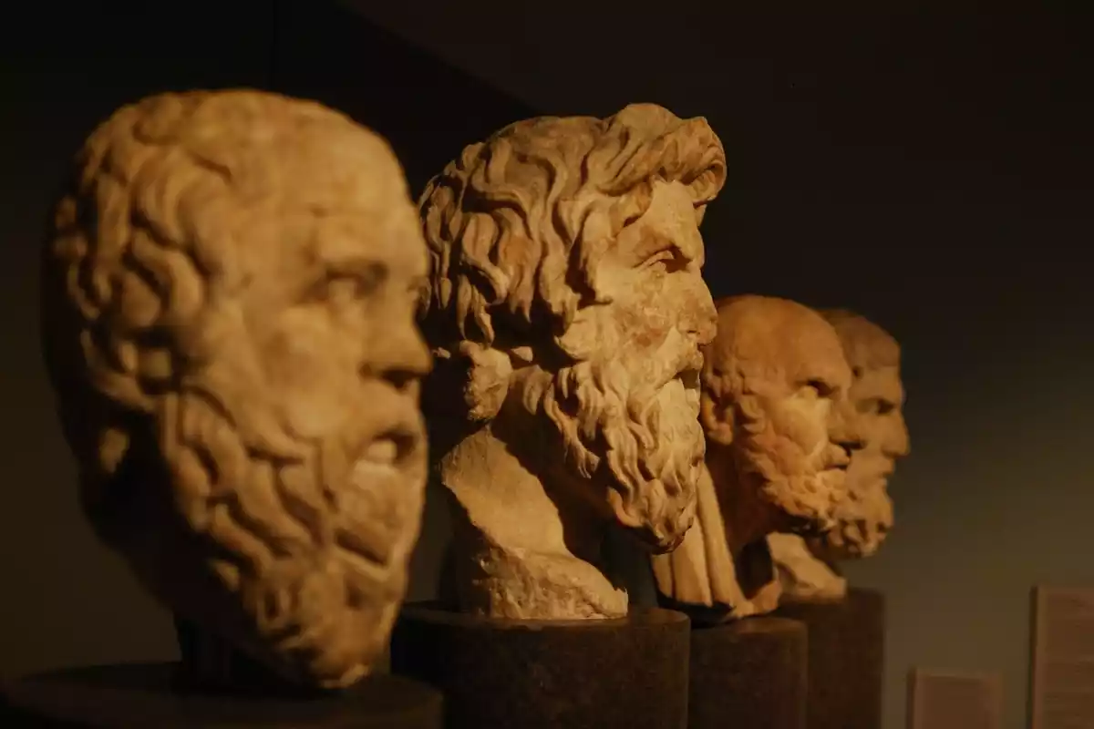 Bustos de grandes filósofos de la Grecia Clásica de mármol y luz naranja encima