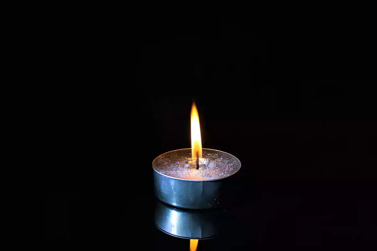 Una vela encendida con fuego en medio de la oscuridad reinante de la noche