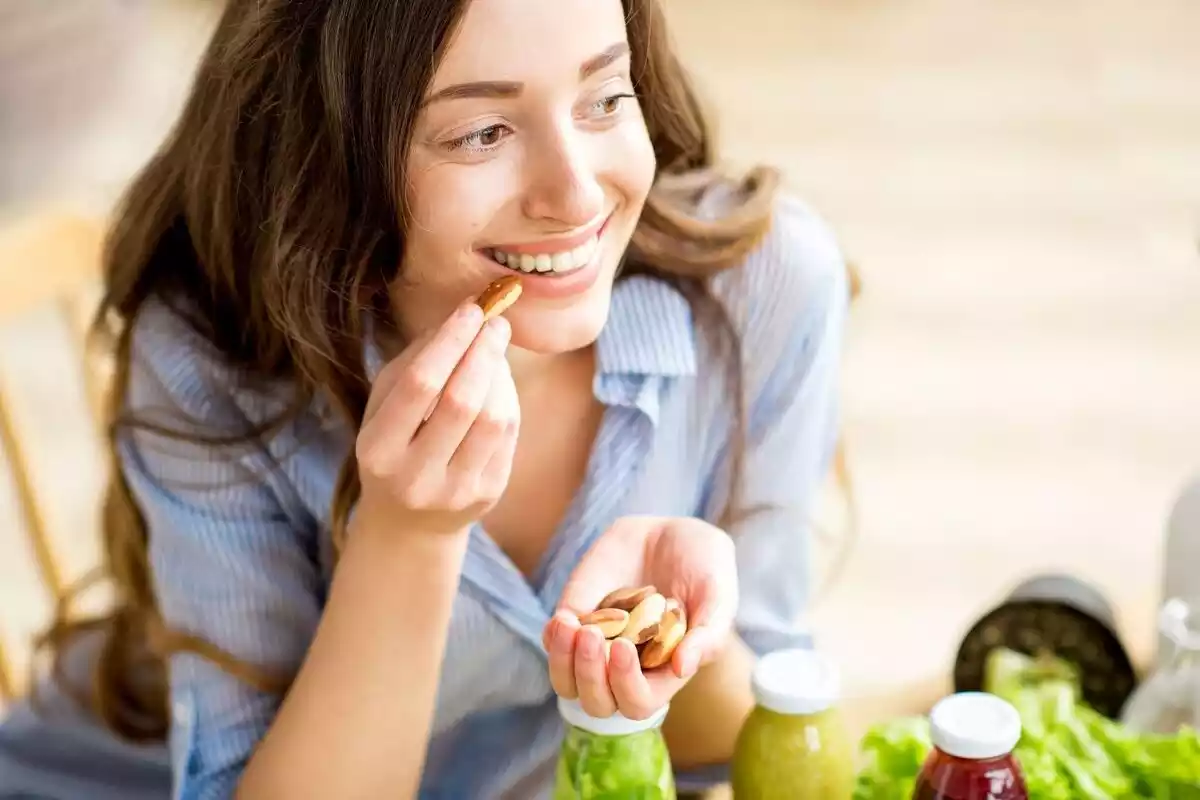 Mujer comiendo frutos secos mientras sonríe