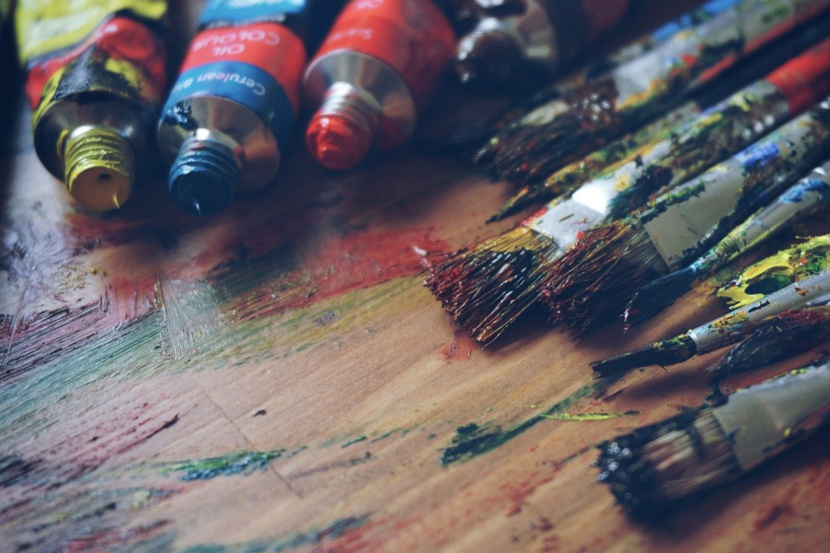 Pintura y pinceles de muchos colores, sobre un soporte de madera ensuciado